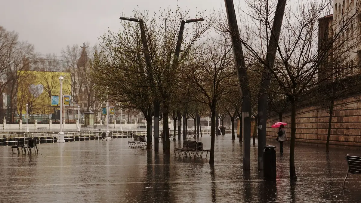Rött paraply på en regnig promenad längs Ría de Bilbao