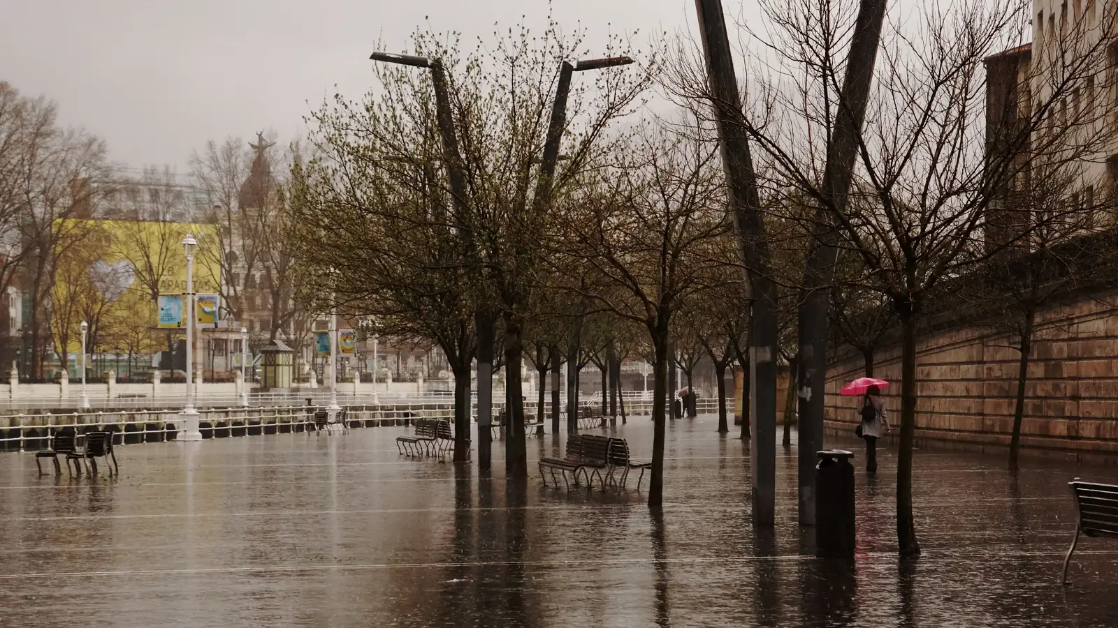 Rött paraply på en regnig promenad längs Ría de Bilbao